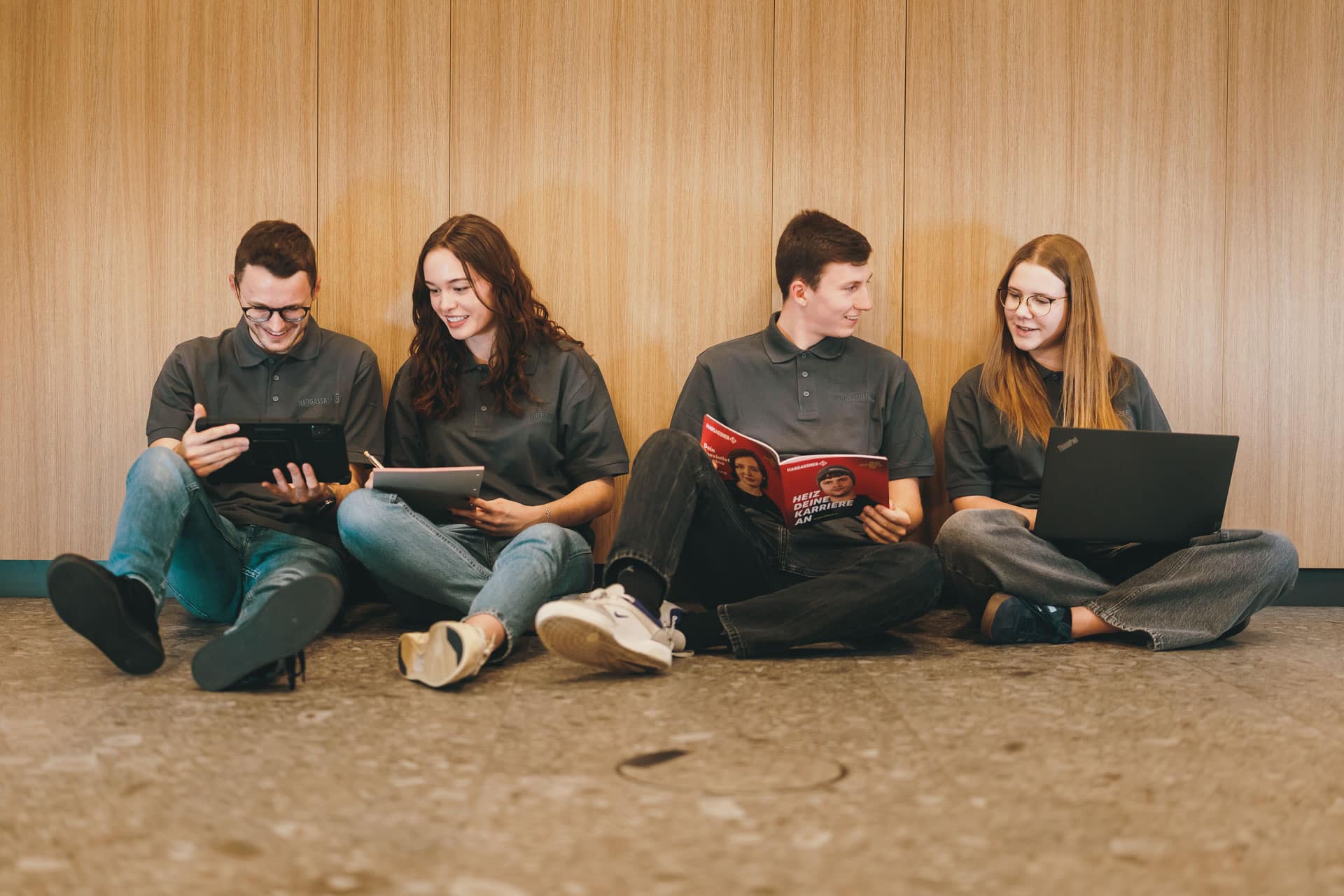 Junge Menschen sitzen am Boden und sehen sich Unterlagen an, Verbildlichung "Jobs für Schüler und Studenten"