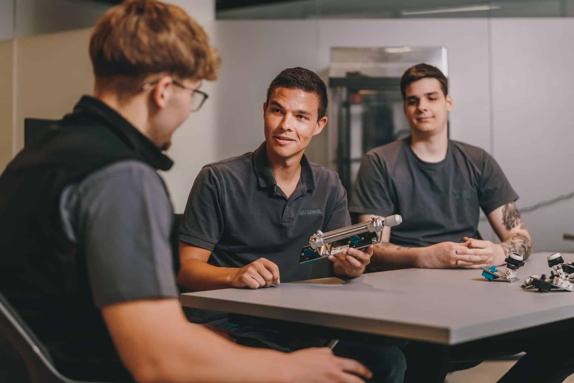 Besprechung in der Hargassner Lehrwerkstatt, Tisch, Werkstück, junge Männer